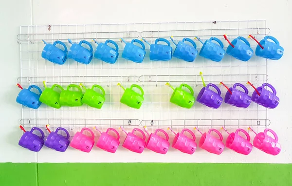 Duvarda asılı diş fırçası ile plastik kupa, renkli