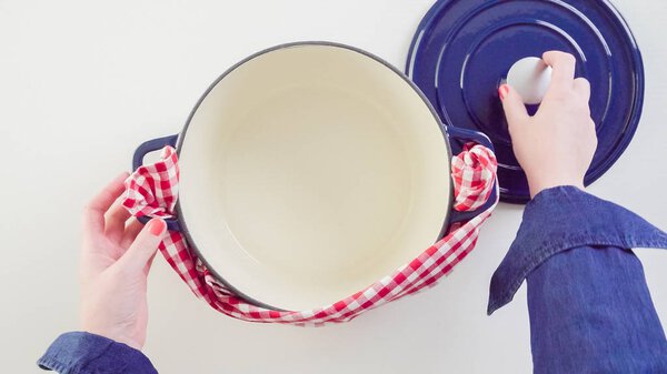 Brand new enameled cast iron covered dutch oven on a white background.