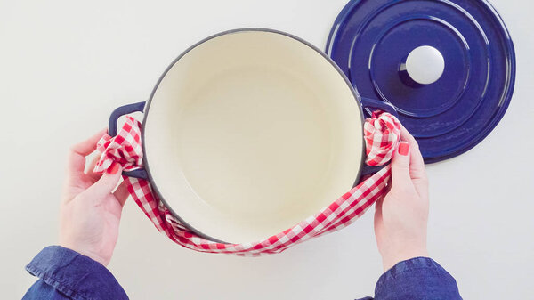 Brand new enameled cast iron covered dutch oven on a white background.