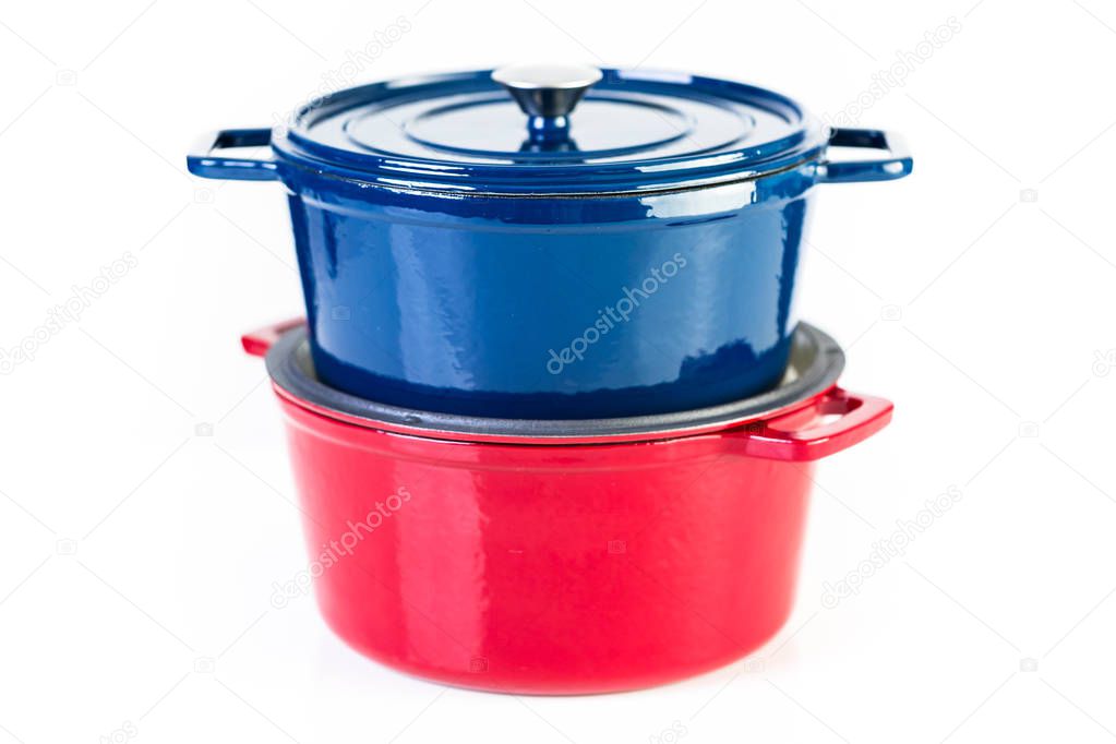 Red and blue enameled cast iron covered dutch ovens on a white background.