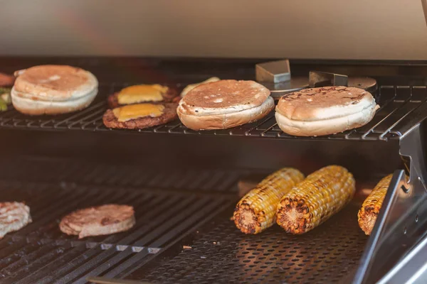 Cozinhar hambúrgueres em churrasqueira a gás ao ar livre — Fotografia de Stock
