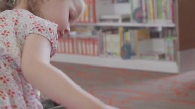 Küçük kız çocuk Halk Kütüphanesi bölümünde oynamak.