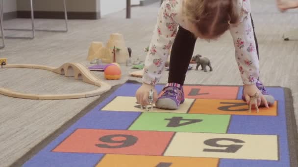 Kleines Mädchen Spielt Auf Teppich Mit Hopscotch Muster — Stockvideo