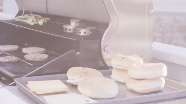一歩一歩 屋外のガスのグリルの隣にあるトレーにハンバーガー — ストック動画