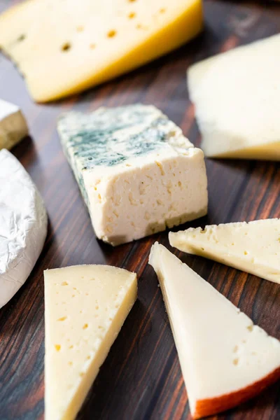 Koyu ahşap arka planda büyük gurme peynir dilimleri var..