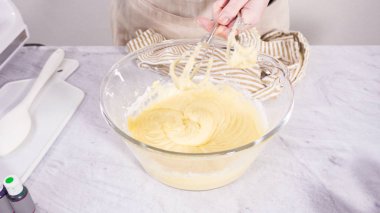 Adım adım. Vanilyalı Mardi Gras kekleri pişirmek için karışımı elektrikli mikserle karıştırıyorum..