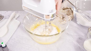 Adım adım. Vanilyalı Mardi Gras kekleri pişirmek için karışımı elektrikli mikserle karıştırıyorum..