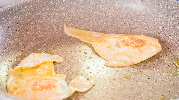 Frying organic egg in olive oil on frying pan.