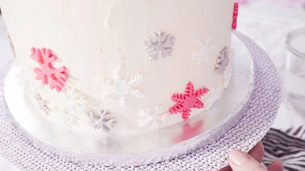 一歩ずつ ピンクと白のフォンダンスノーフレークで丸いFunfettiケーキを飾る — ストック写真