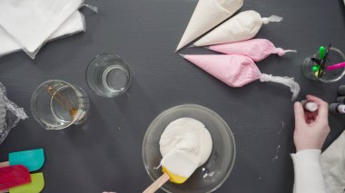 Adım adım. Düz yatıyordu. Şekerli kurabiyeleri süslemek için kraliyet kremasına gıda boyası karıştırmak..