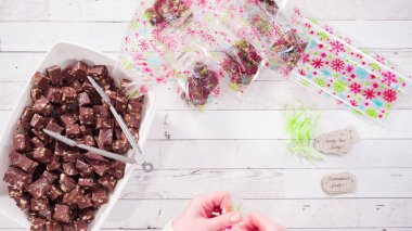 Düz yatıyordu. Adım adım. Ev yapımı macadamia şekerlemesi küçük hediye paketlerine konuyor..