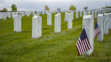 Denver, Colorado, ABD-26 Mayıs 2019 - Anma Günü 'nde Fort Logan Ulusal Mezarlığı' nda beyaz mermer mezar taşlarının yanında küçük Amerikan Bayrakları.