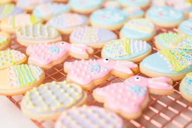 Farklı renklerde kraliyet kremalarıyla süslenmiş Paskalya şekerli kurabiyeler..