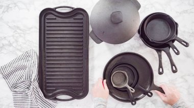 Düz yatıyordu. Mermer tezgahtaki dökme demir mutfak malzemelerinin çeşitliliği.