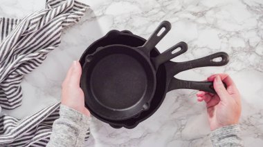 Düz yatıyordu. Mermer tezgahtaki dökme demir mutfak malzemelerinin çeşitliliği.