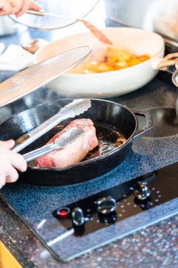 Elektrikli fırının üstünde kızgın demir tavayla New York bifteği kızartıyorum..