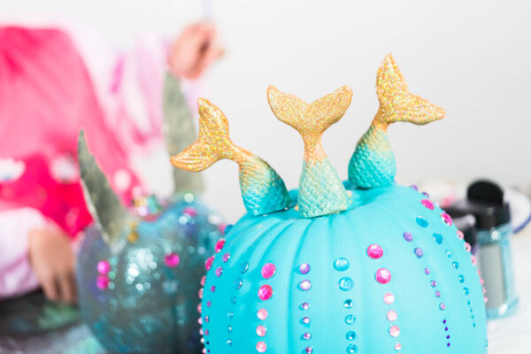 Little girl decorating her Halloween pumpkin with rhinestones.