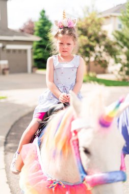 Küçük kız doğum günü partisinde tek boynuzlu ata biniyor..
