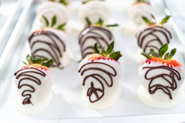 Çikolataya batırılmış organik çilekler parşömen kağıdına kurulanıyor..
