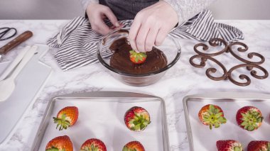 Adım adım. Çikolata kaplı çilek hazırlamak için organik çilekleri erimiş çikolatayla bir kaseye daldırmak..