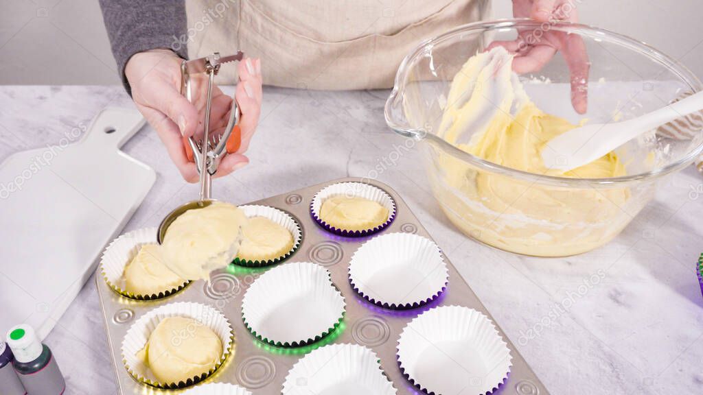 Step by step. Scooping cupcake batter into a foil cupcake liners to bake vanilla Mardi Gras cupcakes.