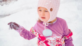 Malá holčička hraje ve sněhu u jejího domu v typické předměstí.