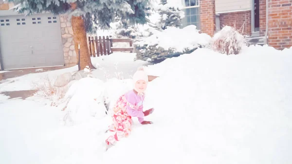 在典型的郊区 小女孩在她家附近的雪中玩耍 — 图库照片