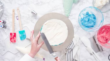 Yuvarlak üç katlı vanilyalı pasta yapmak için pasta katmanları yığılıyor.