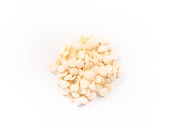 Düz yatıyordu. Beyaz arka planda çikolata şekillerini eritmek için beyaz yuvarlak çikolata parçaları..