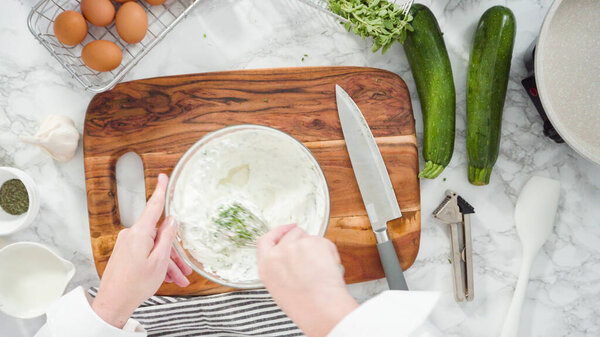 Flat lay. Step by step. Mixing ingredients in a mixing bowl to make zucchini cakes.