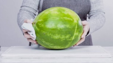 Kırmızı karpuzu beyaz bir kesme tahtasının üzerinde küçük parçalara ayırmak.