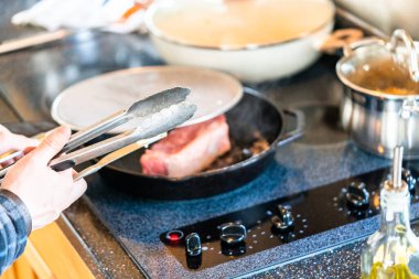 Elektrikli fırının üstünde kızgın demir tavayla New York bifteği kızartıyorum..