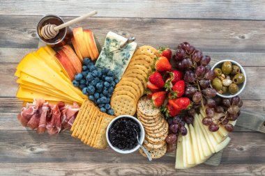 Düz yatıyordu. Aperatif olarak sunulan tahtanın üzerinde gurme peyniri, kraker ve meyve var..