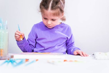 Küçük kız arsilik boya ile tuvale resim yapıyor..
