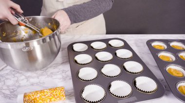 Balkabağı aromalı kek hamuru. Hamur hamuru kepçesiyle kapkek tepsisine dolgu malzemesi..