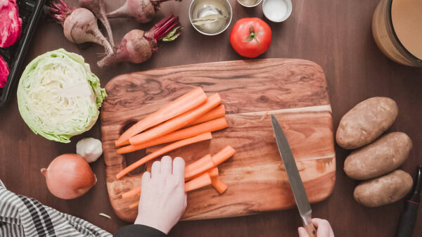 Step by step. Flat lay. Slicing orange carrots into the small cubes for beet soup, borscht.