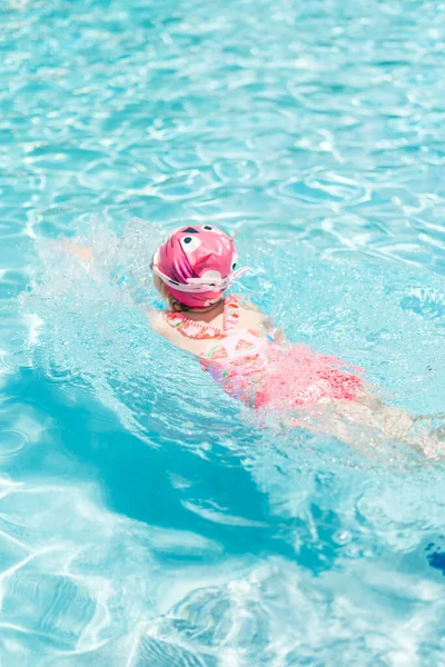 夏の屋外プールで泳ぐピンクの水泳カップとゴーグルの小さな女の子 — ストック写真