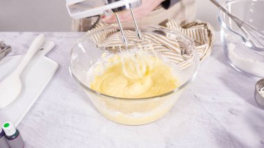 Adım adım. Vanilyalı Mardi Gras kekleri pişirmek için karışımı elektrikli mikserle karıştırıyorum..