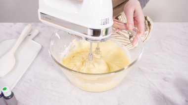 Adım adım. Vanilyalı Mardi Gras kekleri pişirmek için karışımı elektrikli mikserle karıştırıyorum..