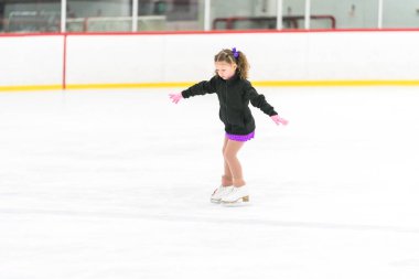 Küçük kız buz pateni pistinde artistik patinaj yapıyor..