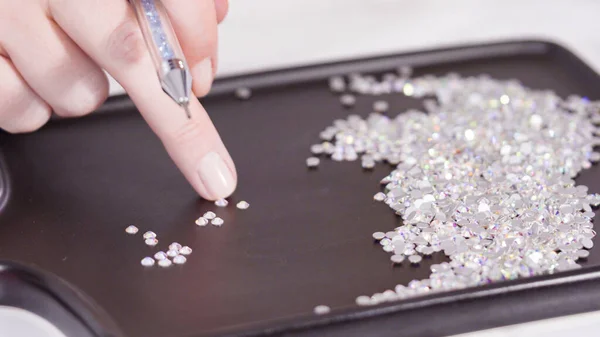 An abundance of white rhinestones with flat back on a black board ready for a craft project.