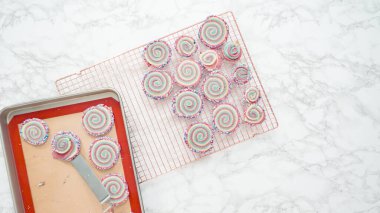 Adım adım. Düz yatıyordu. Soğutucuda taze pişmiş fırın kırmızı, beyaz ve mavi fırıldak şekerli kurabiyeler..