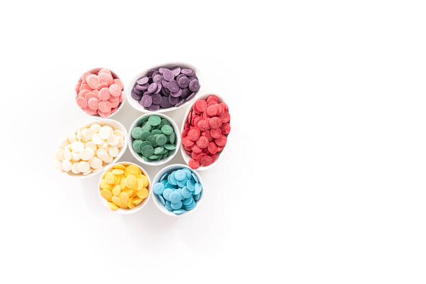Flat lay. Pink round chocolate chips for melting chocolate shapes on a white background.