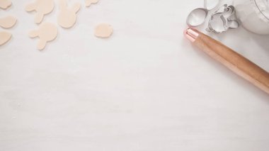 Adım adım. Düz yatıyordu. Paskalya şekilli kurabiye kesicilerle şekerli kurabiye hamuru kesiyorum..