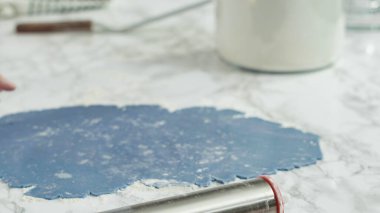 Adım adım. Kırmızı, beyaz ve mavi fırıldak şekerli kurabiyeler pişirmek için hamuru yuvarlıyor..