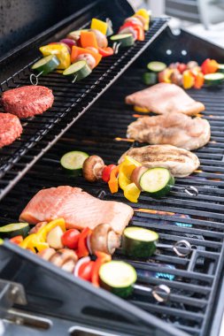 Atlantik somonu, tavuk göğsü, sebze şişi ve açık hava ızgarasında vejetaryen burger ızgarası..