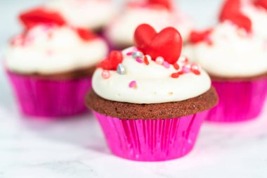 Krem peynirli kırmızı kadife kekler ve kalp ve öpücük şeklinde kırmızı çikolatalarla süslemeler..