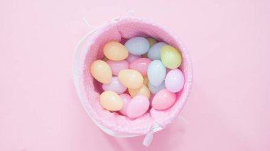 Pembe arka planda plastik yumurtaları olan Paskalya sepeti.