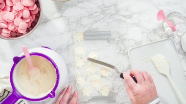 Düz yatıyordu. Adım adım. Erimiş çikolatayı kar taneleri şeklinde plastik bir çikolata kalıbına döküyorum..