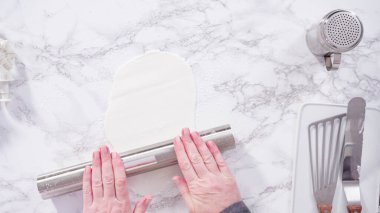 Düz yatıyordu. Adım adım. Beyaz fondantımızı mermer tezgahta yuvarlıyoruz..